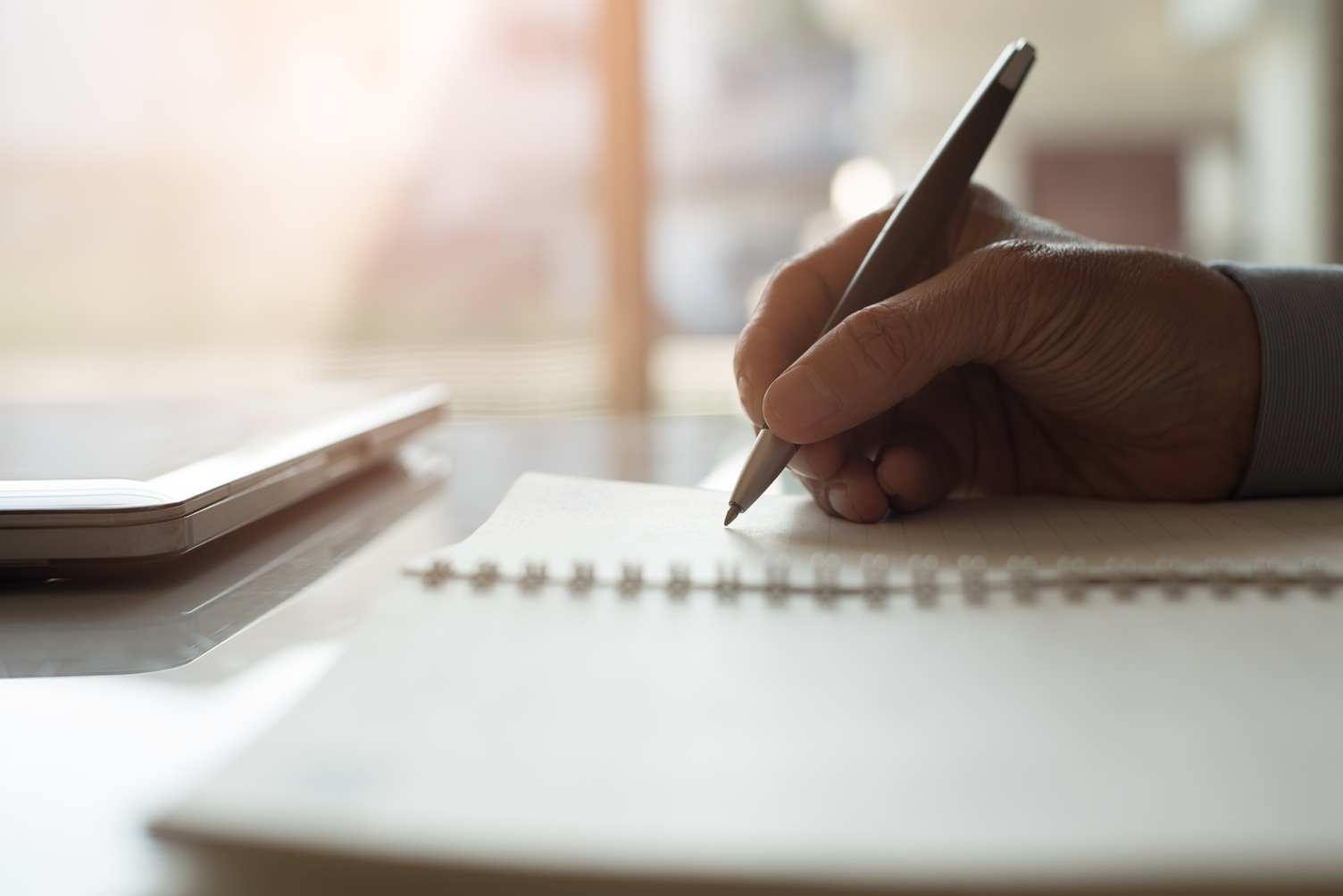 Man writing on notepad Hand schrijft met een potlood in een kladblok—het creatieve proces van een redacteur in actie